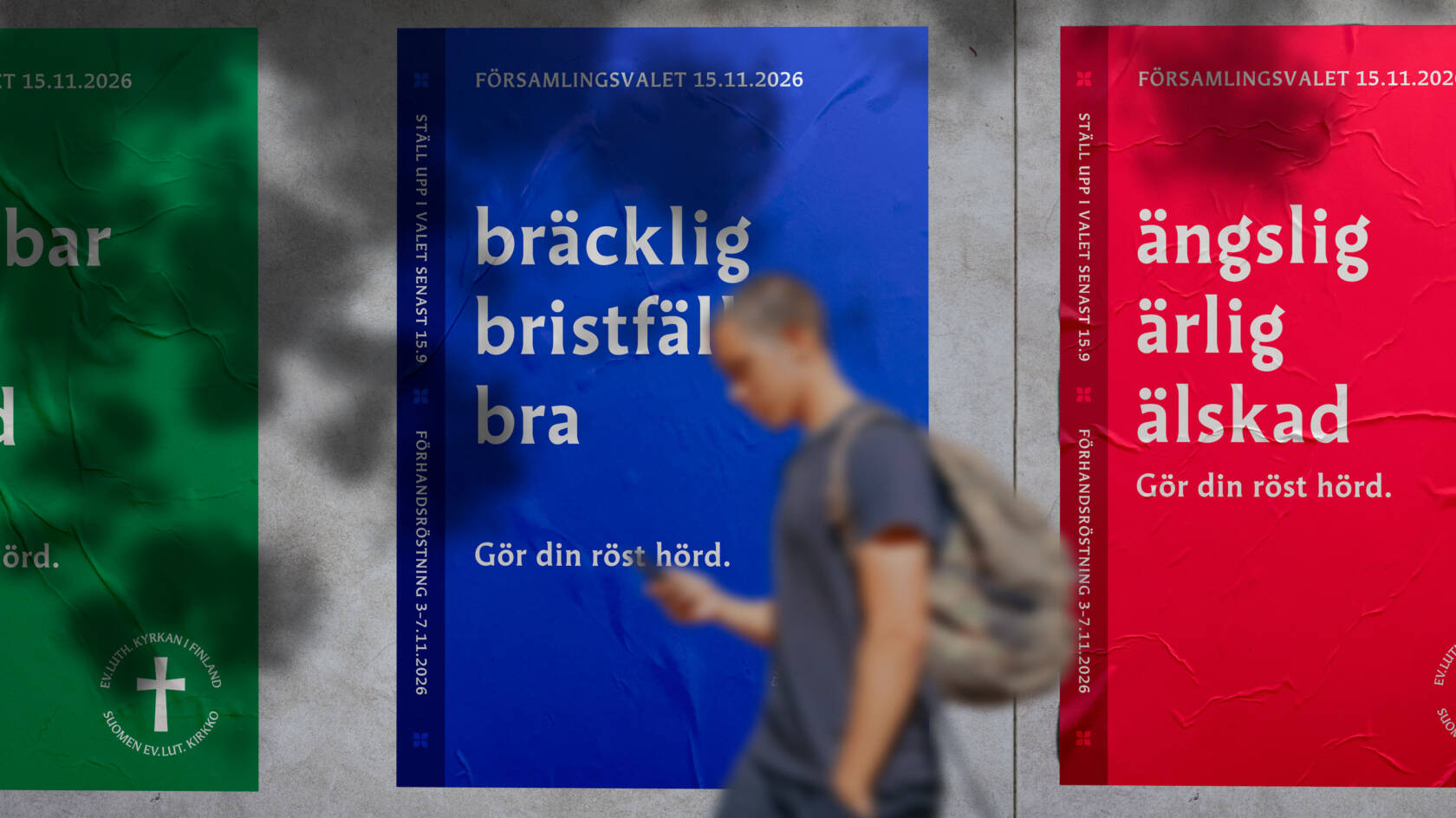 En man går längs en vägg där det syns reklam för församlingsvalet.