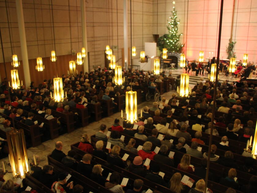 Ihmisiä kirkossa laulamassa joululauluja.