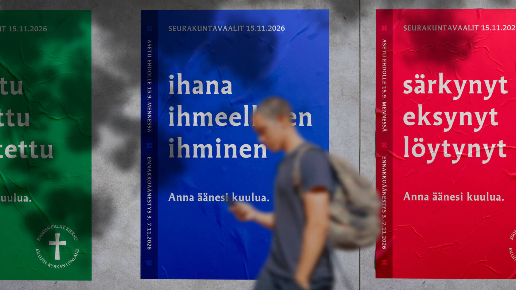 Henkilö kulkee kadulla taustallaan seinään kiinnitetyt seurakuntavaalijulisteet.