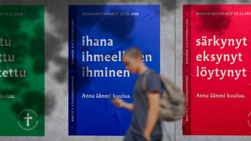 Henkilö kulkee kadulla taustallaan seinään kiinnitetyt seurakuntavaalijulisteet.